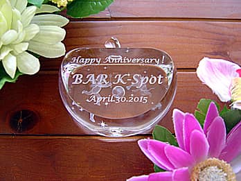「Happy anniversary、店名、日付」を側面に彫刻した、飲食店の周年祝い用のガラス製オブジェ