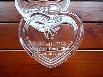 「歯科クリニックの名前とマーク、2nd anniversary」を蓋に彫刻した、周年祝いの贈り物用のガラス製小物入れ