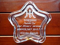「ロゴマーク、Thanks for your 20years'services、永年勤続者の名前」を彫刻した、勤続20年の記念品用のガラス製小物入れ