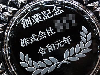 「創業記念 株式会社○○ 令和元年」を底面に彫刻した、創立記念品用のガラス製灰皿