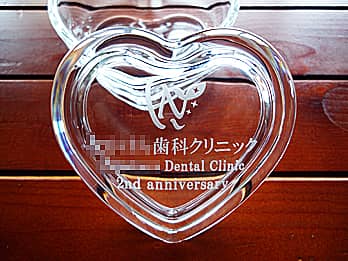 「歯科クリニックの名前とマーク、2nd anniversary」を蓋に彫刻した、周年記念品用のガラス製小物入れ