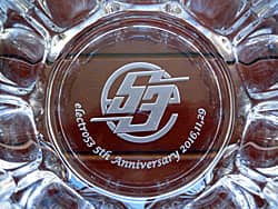 「ロゴマーク、5th anniversary、日付」を底面に彫刻した、お取引先へ贈呈する周年祝いの贈り物用のガラス製灰皿