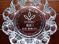 「ロゴマーク、感謝 ○○殿」を底面に彫刻した、永年勤続の記念品用のガラス製灰皿