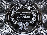 「50th Anniversary of Birth、○○ちゃん、誕生日の日付」を底面に彫刻した、誕生日プレゼント用のガラス製灰皿