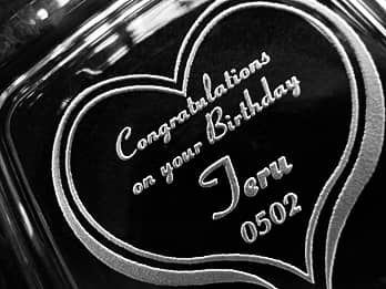 誕生日プレゼント用のガラス製灰皿の底面に彫刻した、「Congratulations on your birthday、贈る相手の名前、誕生日の日付」のクローズアップ画像