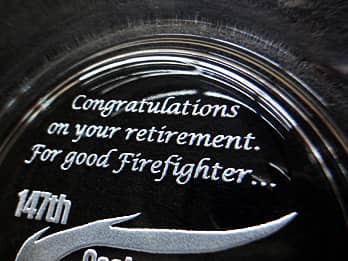 定年退職の贈り物用のガラス製灰皿の底面に彫刻した、「Congratulations on your retirement. For good firefighter. 」のクローズアップ画像