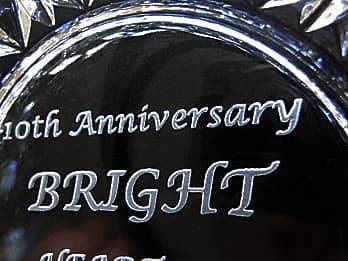周年祝い用のガラス製灰皿の底面に彫刻した、「お祝いメッセージと会社名」のクローズアップ画像