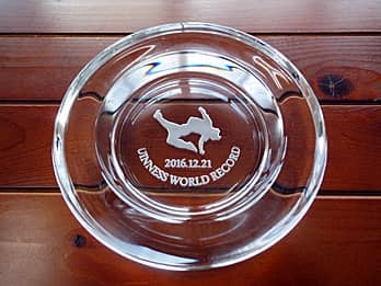 「セパタクローのイラスト、賞の名前、日付」を底面に彫刻した、大会の賞品用のガラス製灰皿