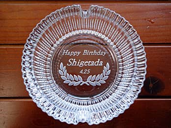 「Happy birthday、贈る相手の名前、誕生日の日付」を底面に彫刻した、誕生日プレゼント用のガラス製灰皿