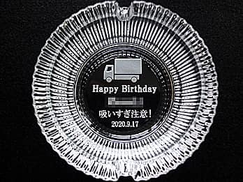 「トラックのイラスト、Happy Birthday、贈る相手の名前、吸いすぎ注意、誕生日の日付」を底面に彫刻した、誕生日プレゼント用のガラス製灰皿