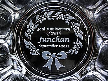 「50th anniversary of birth、贈る相手の名前、誕生日の日付」を底面に彫刻した、誕生日プレゼント用のガラス製灰皿