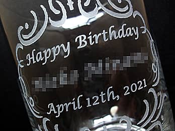 誕生日プレゼント用のフラワーベースの側面に彫刻した「Happy Birthday、贈る相手の名前、誕生日の日付」のクローズアップ画像