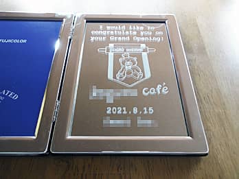 「カフェのロゴマーク」と「お祝いメッセージ、開店日の日付」を彫刻した、カフェの開店祝いのプレゼント用のブック型写真立て