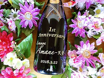 「1st anniversary、お店のロゴ、日付」を側面に彫刻した、周年祝い用のシャンパンボトル