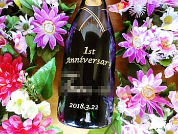 「1st anniversary、奥さまと旦那様の名前」を側面に彫刻した、結婚記念日のプレゼント用のシャンパンボトル