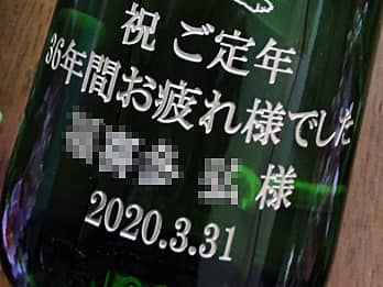 定年退職祝い用の日本酒の一升瓶側面に彫刻した、「感謝を込めたメッセージ（祝ご定年 36年間お疲れ様でした）、定年退職する方の名前（○○様）、日付（2020.3.31）」のクローズアップ画像