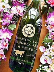 「○○お父さん卒寿 ○○お母さん米寿、贈り主の名前」と「家紋と猫のイラスト」を一升瓶の側面に彫刻した、両親の卒寿と米寿のお祝い用の日本酒