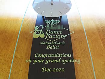 「ロゴマーク」と「Congratulations on your grand opening」を前面ガラスに彫刻した、バレエ教室の開業祝い用の掛け時計