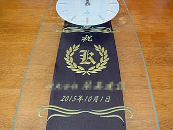 「祝○○賞、日付、月桂樹の飾り」を前面ガラスに彫刻した、賞品用の掛け時計