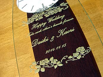 「Happy wedding、新郎と新婦の名前、挙式日」を前面ガラスに彫刻した、結婚祝い用の掛け時計
