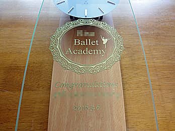 「バレエスクールのマーク、Congratulations、受賞者名」を前面ガラスに彫刻した、バレエの発表会の賞品用の掛け時計