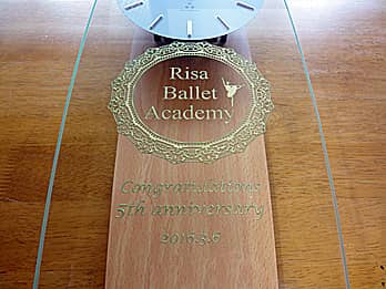 ロゴマークを前面ガラスに彫刻した、バレエ教室の周年祝い用の掛け時計