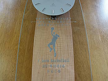 部活顧問の先生の古希祝い用の掛け時計（バスケットボールのシュートシーンのイラストとお祝いメッセージを、掛け時計の前面ガラスに彫刻）