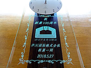 「祝 創業100周年、○○株式会社、ロゴマーク」を彫刻した、周年祝い用の掛け時計