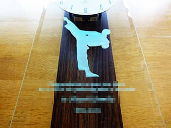 競技シーンのイラストを前面ガラスに彫刻した、表彰記念品用の掛け時計