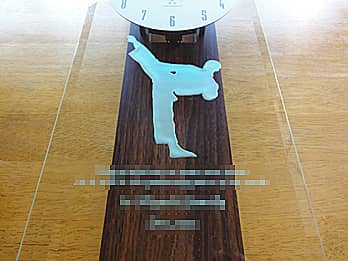 空手の蹴りのイラストを前面ガラスに彫刻した、卒業生から部に寄贈する掛け時計