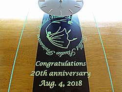 「Congratulations! 20th anniversary」「ロゴマーク」を前面ガラスに彫刻した、バレエ教室の20周年祝い用の掛け時計