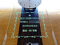 「祝 NPO法人○○、日付、職員一同」を彫刻した、NPO法人の周年祝い用の掛け時計