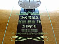 「功労者記念、○○様、株式会社○○」を前面ガラスに彫刻した、表彰記念品用の掛け時計