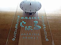 「お店のロゴ」と「祝開店4周年、○○より」を彫刻した、飲食店の周年祝い用の掛け時計