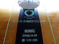 「クリニックのロゴマーク」と「祝開院 2019.11.01 贈○○」を前面ガラスに彫刻した、開院祝い用の掛け時計