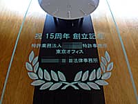 「祝 15周年 創立記念 特許業務法人○○特許事務所、贈り主の会社名」を前面ガラスに彫刻した、特許事務所の周年祝い用の掛け時計