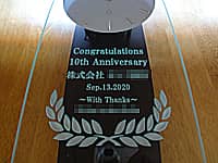 「Congratulations 10th Anniversary、株式会社○○設計、贈り主の名前」を前面ガラスに彫刻した、設計会社の周年祝い用の掛け時計