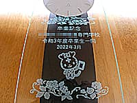 「卒業記念 ○○専門学校 令和3年度卒業生一同」と「マスコットキャラクター」を前面ガラスに彫刻した、卒業生から学校へ寄贈する振り子時計