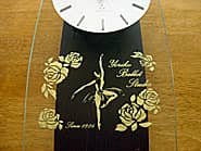 バレリーナとバラの花のイラストを前面ガラスに彫刻した、バレエ教室の周年祝い用の掛け時計