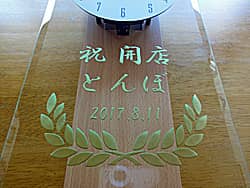 「祝開店、店名、日付」を前面ガラスに彫刻した、居酒屋の開店祝い用の掛け時計