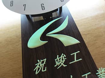 竣工祝い用の掛け時計に彫刻した、会社のマークのクローズアップ画像