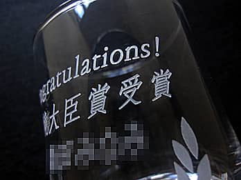 表彰記念品用のグラスの側面に彫刻した「お祝いメッセージと表彰内容」のクローズアップ画像
