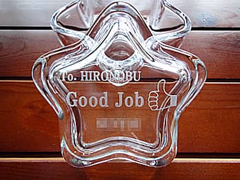 「永年勤続者の名前、サムアップのイラスト、会社名」を蓋に彫刻した、永年勤続表彰用のガラス製小物入れ