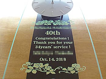 「勤続年数、感謝を込めたメッセージ、永年勤続者の名前、表彰日の日付」を前面ガラスに彫刻して完成した、永年勤続表彰用の掛け時計