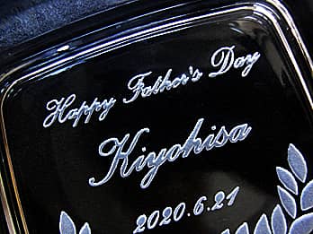 父の日のプレゼント用のガラス製灰皿の底面に彫刻した、「お祝いメッセージ、お父さんの名前、父の日の日付」のクローズアップ画像