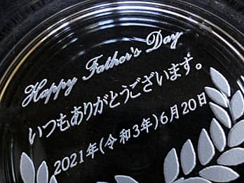 父の日のプレゼント用のガラス製灰皿の底面に彫刻した、「お父さんへの感謝を込めたメッセージと、父の日の日付」のクローズアップ画像
