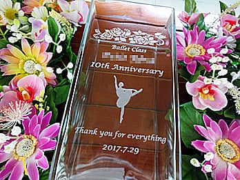 「バレリーナのイラスト」と「お祝いメッセージ、バレエ教室の名前、日付」を側面に彫刻した、バレエ教室の周年祝い用のガラス花瓶