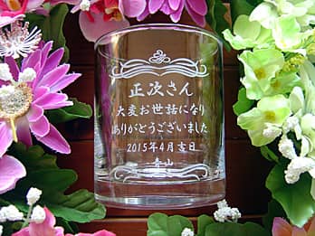 「○○さん 大変お世話になり、ありがとうございました」を側面に彫刻した、定年退職のお祝い品用の名入れロックグラス