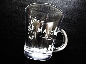 「店名とマーク」を側面に彫刻した、ガラス製のティーカップ