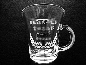 「勤続20周年記念、○○様、贈呈日の日付」を側面に彫刻した、永年勤続表彰用のガラス製ティーカップ
